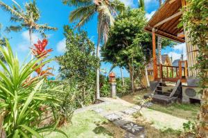 d'un jardin tropical avec une maison dotée d'une terrasse couverte. dans l'établissement Atuh Forest Cottage, à Nusa Penida