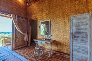 Schlafzimmer mit einem Schreibtisch, einem Bett und einem Fenster in der Unterkunft Atuh Forest Cottage in Nusa Penida