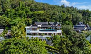 a house in the middle of a hill with trees at Baan Phu Prana Boutique Villa in Surin Beach