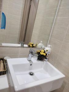 lavabo blanco en el baño con espejo en BOM HOMES- VINHOMES OCEAN PARK- SERVICE APARTMENt, en Gia Lâm Pho