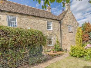 an old brick house with a hedge in front of it at Middle Cottage in Easton on the Hill