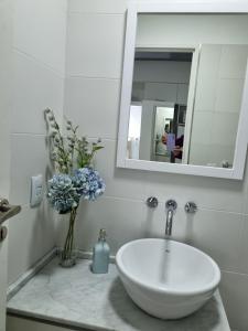a bathroom with a sink and a mirror and flowers at Departamento Vera Mujica 3 cochera propia incluida in Rosario +5 photos