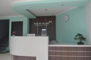 um escritório com um balcão e um relógio na parede em PUNCAK VILLAGE HOTEL & KAMPUNG MAIN ANAK em Gadok 1