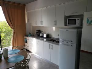 a kitchen with white cabinets and a table and a refrigerator at Departamento Vera Mujica 3 cochera propia incluida in Rosario
