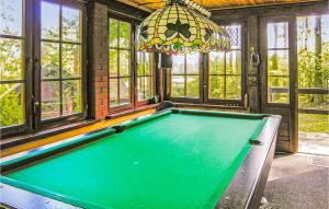 a pool table in a room with windows and a chandelier at Nice Home In Grunwald With 3 Bedrooms And Wifi in Mielno