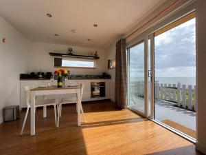 cocina con mesa y vistas al océano en Sunrise Summerhouse, en Balintore