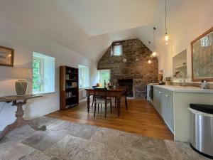 a kitchen with a table and a stone fireplace at Old Manse Cottage in Auchterneed
