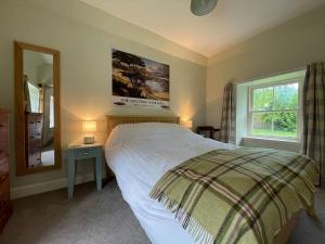 a bedroom with a bed and a mirror and a window at Old Manse Cottage in Auchterneed