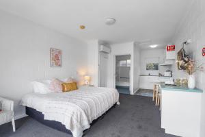 a white bedroom with a bed and a kitchen at Mibnb Geelong CBD Spacious Studio Apartments in Geelong