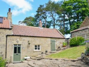 an old stone cottage with green doors and a yard at The Old Back Kitchen At Bonfield Ghyll Farm in Chop Gate