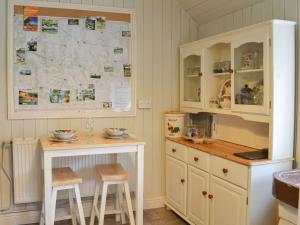 a kitchen with a table and a counter with stools at The Old Back Kitchen At Bonfield Ghyll Farm in Chop Gate