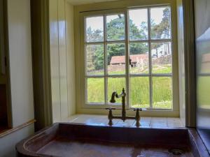 a bath tub in a room with a window at The Old Back Kitchen At Bonfield Ghyll Farm in Chop Gate