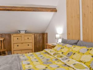 a bedroom with a bed with yellow and white sheets and a dresser at The Old Back Kitchen At Bonfield Ghyll Farm in Chop Gate