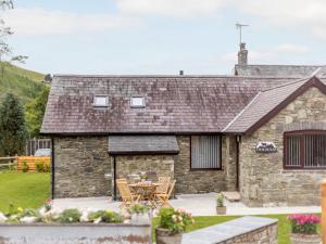 a stone cottage with a table and chairs in front of it at Cwm Dulas in Llanddewi-Brefi