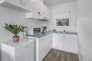 a kitchen with white cabinets and a potted plant at Mibnb Geelong CBD Spacious Studio Apartments in Geelong +28 photos