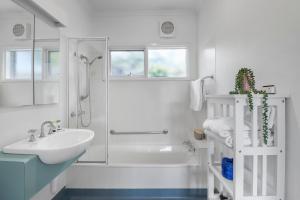 a white bathroom with a sink and a shower at Mibnb Geelong CBD Spacious Studio Apartments in Geelong