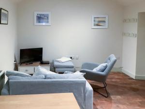 a living room with a couch and two chairs at Bramble Cottage in Ingoldisthorpe