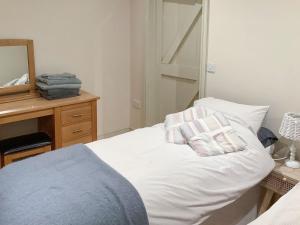 a bedroom with a white bed with two pillows on it at Bramble Cottage in Ingoldisthorpe