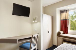 a room with a desk and a chair and a tv at Microtel Inn By Wyndham Louisville East in Louisville