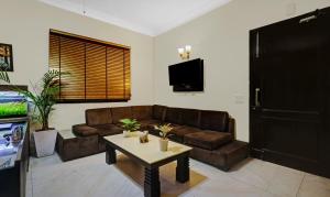 sala de estar con sofá marrón y mesa en Itsy By Treebo - Connaught Mews en Nueva Delhi