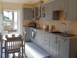 a kitchen with white cabinets and a table with chairs at Stabal Rhoswen in Ffestiniog