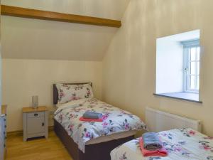 a small bedroom with two beds and a window at Stabal Rhoswen in Ffestiniog