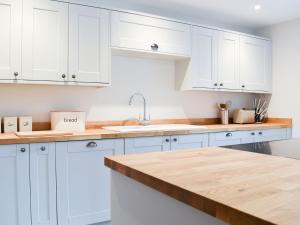 a kitchen with white cabinets and a wooden counter top at The Old Stables 3 - Uk35690 in West Winterslow