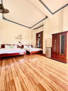 a large room with two beds and a wooden floor at EVA Hotel in Hue