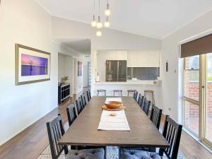 a kitchen and dining room with a wooden table and chairs at Nottage Cottage in Branxton