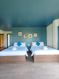 a bedroom with two beds and a blue wall at Nha Bong Villa in Hoi An