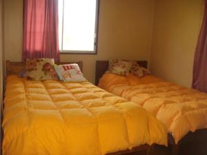 dos camas sentadas una al lado de la otra en un dormitorio en Cabañas Varua, en Hanga Roa