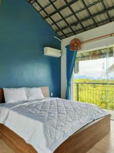 a bedroom with a bed with a blue wall and a window at Nha Bong Villa in Hoi An