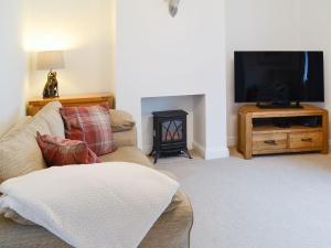 a living room with a couch and a tv at Thistle Cottage in Portpatrick