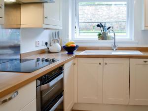 a kitchen with a sink and a stove top oven at Thistle Cottage in Portpatrick