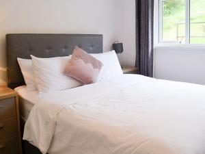un letto bianco con cuscini bianchi e una finestra di Thistle Cottage a Portpatrick