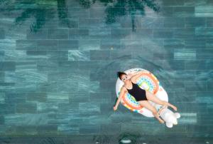 a woman laying on a raft in a swimming pool at The Stay Saigon Riverfront in Gò Công