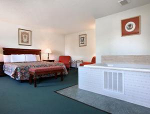 a hotel room with a bed and a bath tub at Travelodge by Wyndham Waukegan Gurnee in Waukegan