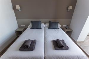 a large white bed with two pillows and towels on it at Hostalin Barcelona Passeig de Gràcia in Barcelona