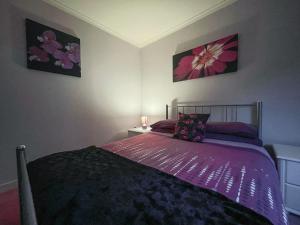 Bervie Road Cottage في كينلوتشبيرفي: غرفة نوم مع سرير مع لحاف أرجواني