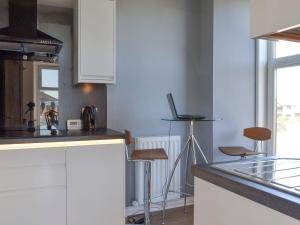 a kitchen with white cabinets and a counter with stools at Inver House Apartment in Inverurie
