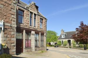 an old stone house on a street in a village at Inver House Apartment in Inverurie