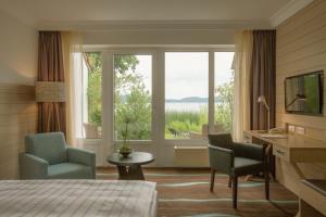 a hotel room with a bed and two chairs and a window at Hotel Der Seehof in Ratzeburg