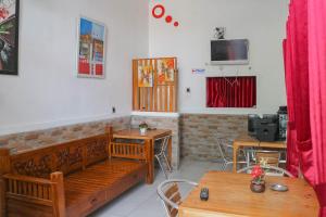 um quarto com bancos e mesas de madeira e uma televisão em Wisma Vandera Syariah Garut Mitra RedDoorz em Garut