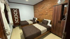 una camera con due letti e un muro di mattoni di Homestay Candi Pawon Murtakim Syariah a Mendut