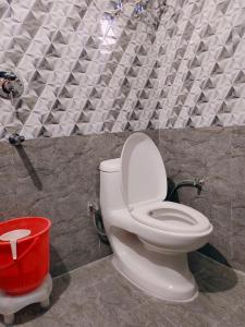 a bathroom with a toilet and a red bucket at Vidya Guest House in Katra