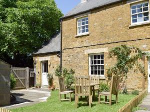 a table and chairs in front of a brick house at Cooks Cottage in Knossington