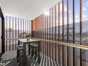 Un balcón con mesa y taburetes. en 541 - 3 Bedroom Townhouse - Centrally Located- Free Parking - Free WIFI, en Torquay