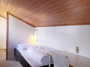 a bedroom with a bed with a table and a wooden ceiling at Holiday home Væggerløse CCXIII in Marielyst
