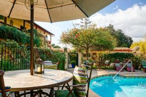 a patio table with an umbrella next to a pool at Blue Iguana Inn in Ojai