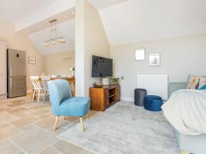 a bedroom with a blue chair and a living room at Tadpole Mews At Frog Hall in Tilston